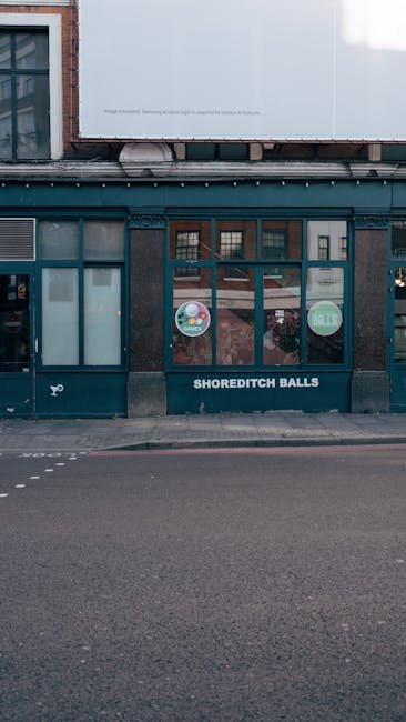 Facade of a floral shop named 'Shoreditch Balls' in Shoreditch, London, with large display windows featuring colorful circular decals promoting flowers and sale offers. The shop has a dark exterior wi